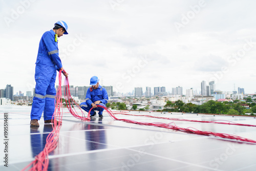 Solar technicians installing electrical cables on rooftop solar panels