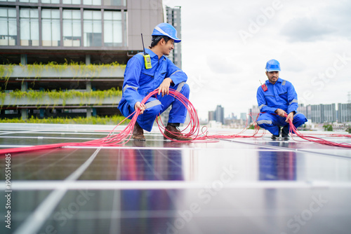 Solar technicians installing electrical cables on rooftop solar panels
