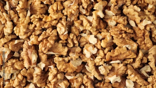 Human hand picking a delicious shelled walnut from a pile of nuts for a healthy vegan snack.