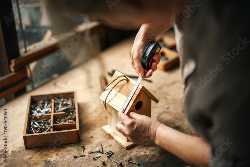 Schilderij op canvas Woman artisan measuring wood to make homemade birdhouse in workshop