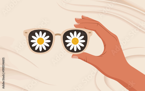 A hand holding sunglasses with daisies reflected in the lenses against a wavy background