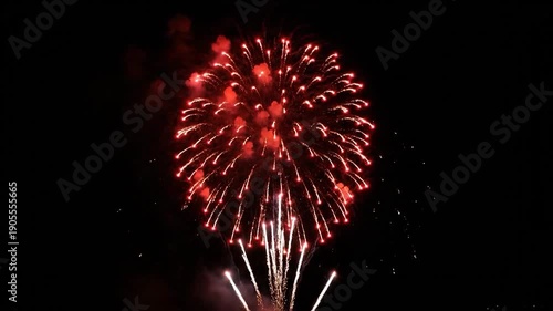 Three colorful aerial fireworks explode against a vast black night sky, radiating light