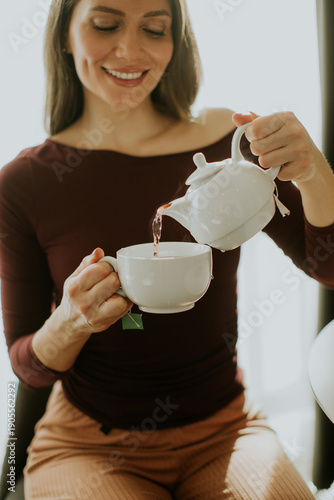 Woman pours tea from a teap...