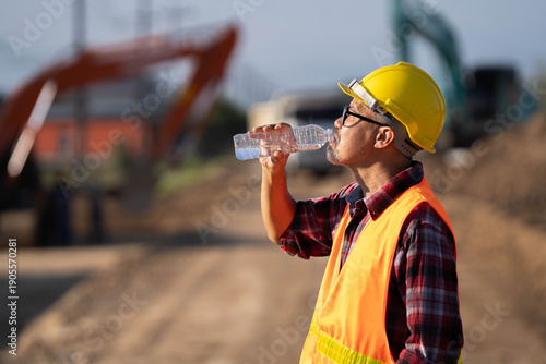 Foto Tired engineer sitting on ground at construction site, feeling hot and thirsty