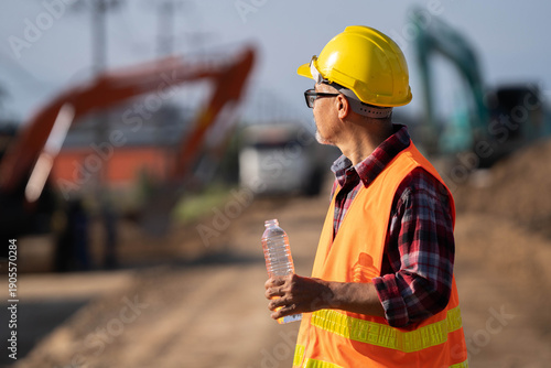 Bilde på lerret Tired engineer sitting on ground at construction site, feeling hot and thirsty