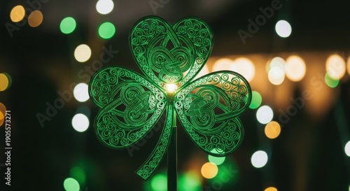 A green shamrock decoration with intricate designs glows brightly against a blurred background of colorful lights.
