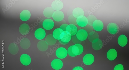 A vibrant and dynamic abstract image featuring numerous bright green dots scattered across a dark gray background with a subtle gradient effect