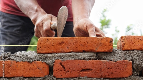 Quadro su tela Close-up of skilled bricklayer working on construction site laying bricks for wa