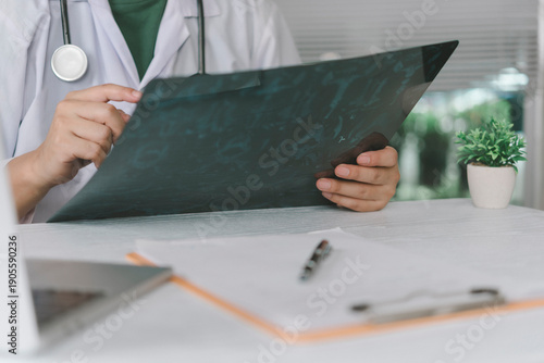 Fotografía Male doctor holding and examining chest x-ray film at medical office desk