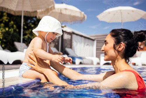 Εκτύπωση καμβά Mother and infant enjoying playful moments in a swimming pool, surrounded by sun