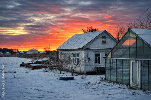 Winter Village at Sunset with Snow Covered Houses and Dramatic Sky