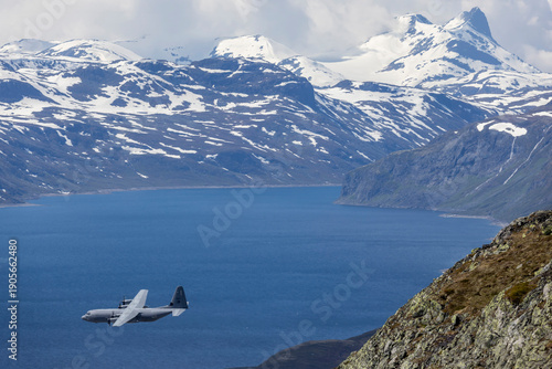 Military Transport Aircraft over Norwegian Mountain Lake in Jotunheimen National Park.
