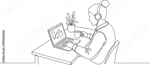Woman wearing headphones works remotely on a laptop while holding a cup of coffee next to a small potted plant at her desk