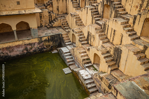 Obraz na plátně Old Indian stepwell with symmetrical stone stairs and murky green water