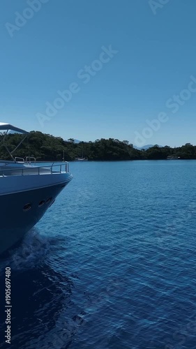 Luxury yacht cruising on a clear blue sea with lush green islands in the background