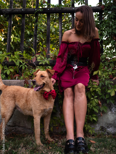 Woman In Red Dress With Dog Posing in front of green gate