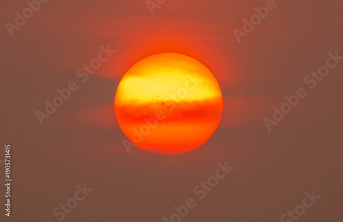 A large orange sun in a hazy sky