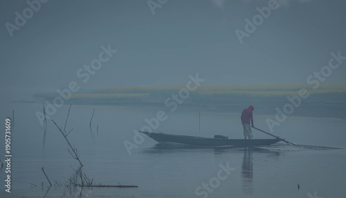A person in a red jacket is standing on a small boat in the water