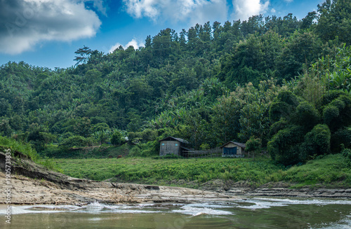 A small house on the riverbank surrounded by lush green trees