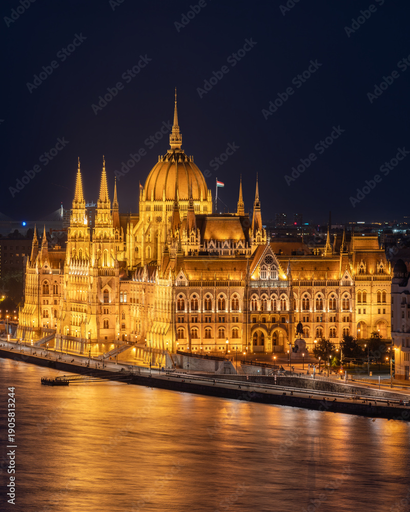 Fototapeta premium Blue hour view of the Hungarian Parliament illuminated along the Danube River. A majestic European cityscape showcasing Budapest iconic architecture at twilight