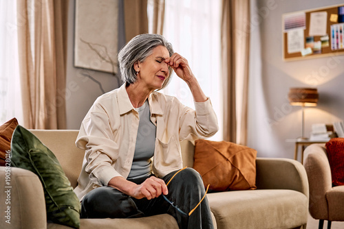 Fotografie A woman sitting on the sofa suffering from a headache