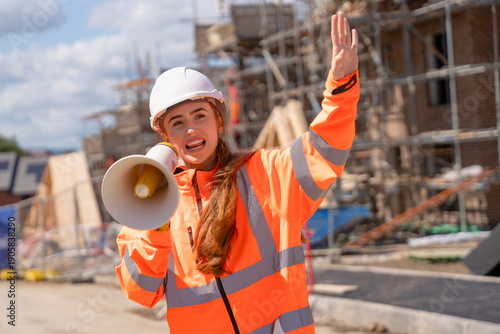 Photography Builder woman girl in orange jacket screaming in megaphone loudspeacker on const