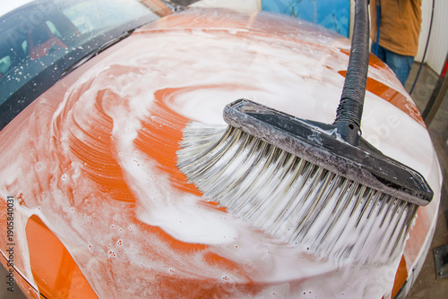 Photos Cleaning a car with a brush at a wash station on a sunny day in the afternoon