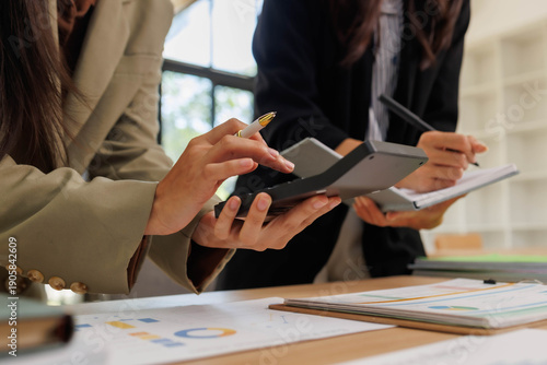 Two women are discussing and working on a presentation filled with graphs and charts. They are writing 