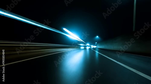 Speeding vehicles create light trails on a highway at night, blue hues and motion