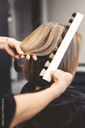 Close up professional colorist selecting perfect hair dye shade from color palette. Focus on hands and swatches for color match before coloring service