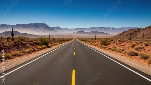 A long straight highway stretches into the desert landscape under a clear blue sky