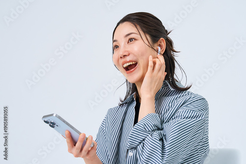 イヤホンを装着してスマートフォンを手にする若い女性