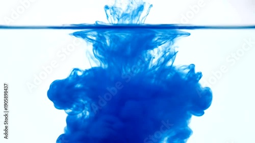 Blue Ink Dropping into Clear Water and Spreading Out.