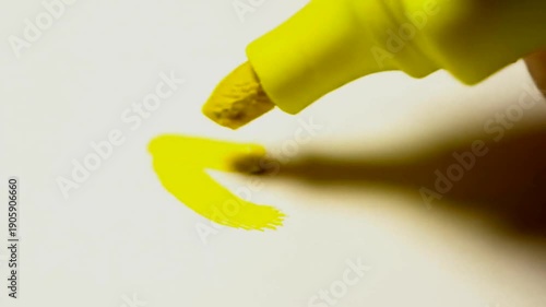Close-up of a yellow highlighter marking on white paper, creating a bright, vibrant line.