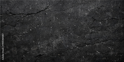 A dark and rough old black asphalt texture shows a weathered grey stone pattern on a grunge street road surface material with a detailed granite and concrete design wallpaper closeup