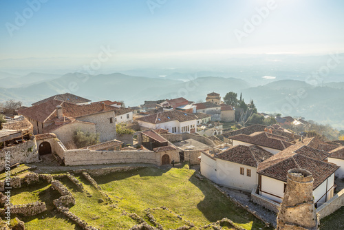 Ancient mountain settlement with traditional stone buildings, castle ruins and defensive walls overlooking a scenic Balkan landscape in daylight, Kruja, Albania