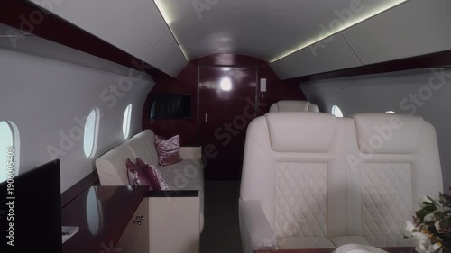 Luxurious private jet interior showcasing elegant seating, plush cushions, and a beautifully arranged dining table with floral centerpiece, illuminated by soft ambient lighting