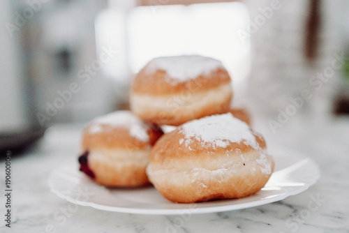 Traditional Polish donuts with powdered sugar on white plate, Fat Thursday dessert, shallow depth of field