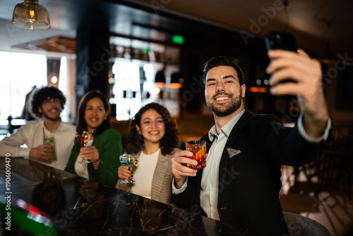Photos Group of friends taking selfie and enjoying cocktails at bar