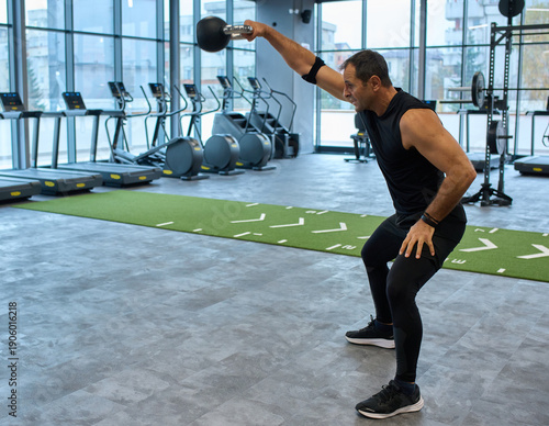 Man doing kettlebell swings at fitness gym