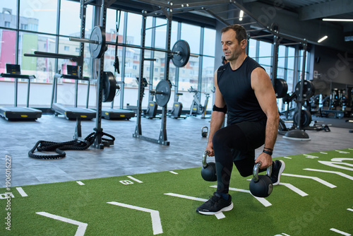 Man doing lunges with kettlebells at gym