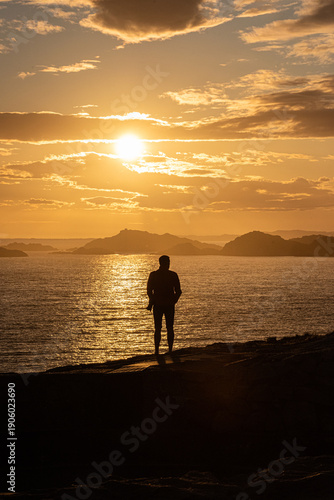 Foto Silhouette of lone man watching golden ocean sunset.