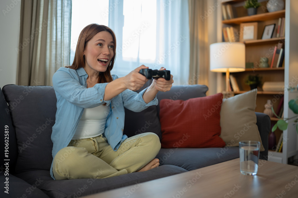 Obraz premium Woman enjoying video game playing on living room couch