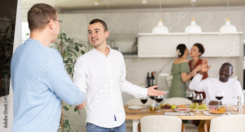 Φωτογραφία Genial young man in casual attire extending warm handshake to friend, welcoming