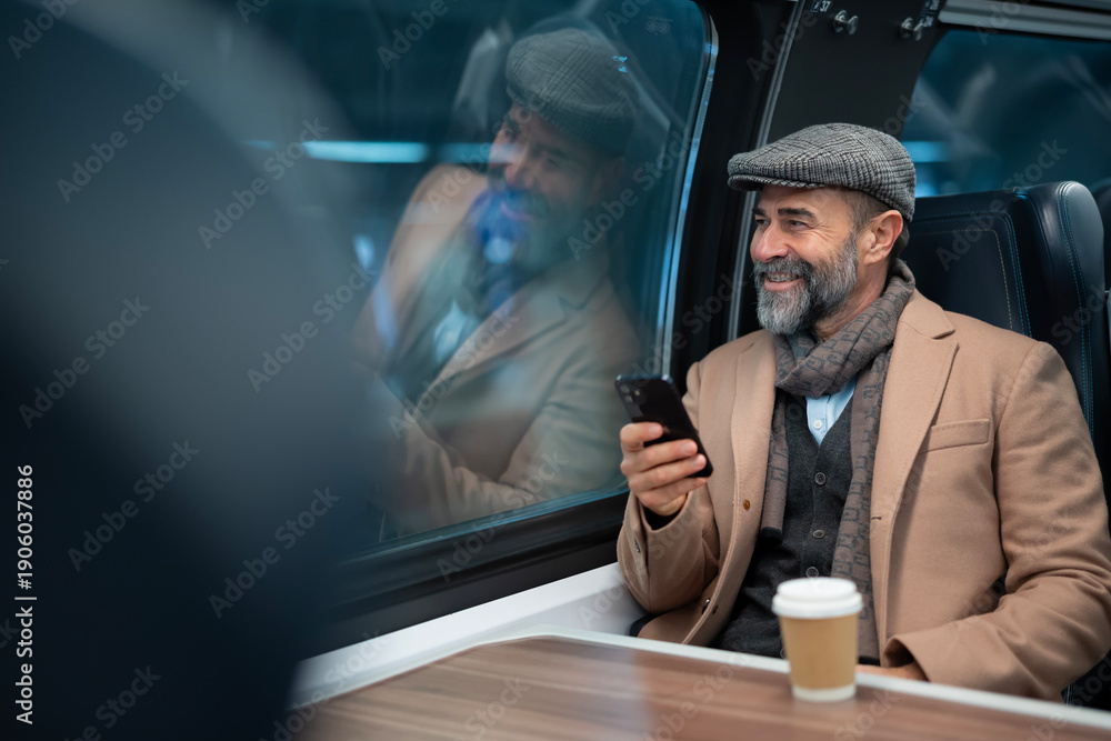 Fototapeta premium Mature man traveling by train using mobile phone