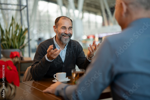 Mature man talking to colleague over coffee