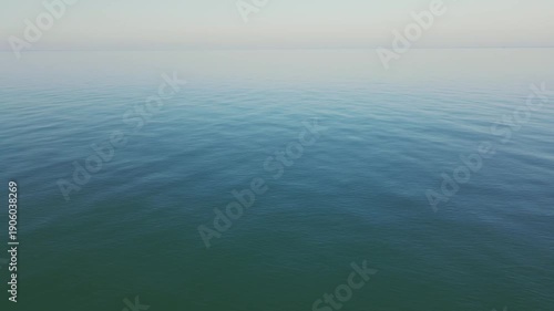 Aerial view of calm azure sea with gentle waves in warm autumn daylight, Batumi Georgia. Minimal 4K drone shot with peaceful meditative mood.