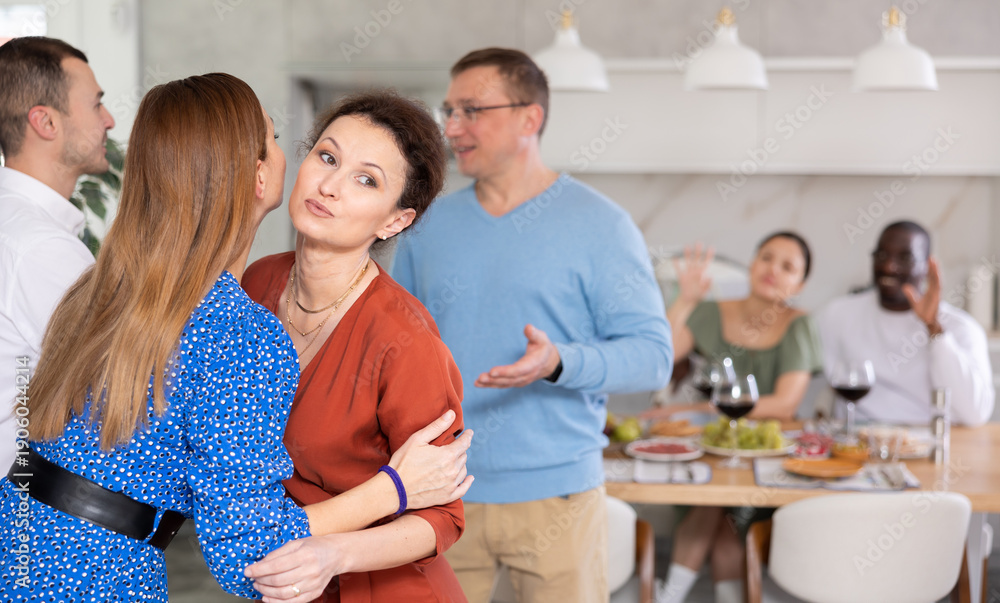 Fototapeta premium Happy middle-aged pair welcoming their guests during small gathering with close friends at home