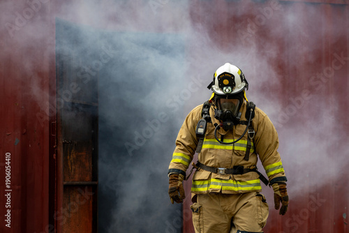 Photos Portrait of firefighter in fireproof clothe walking out of the burning building
