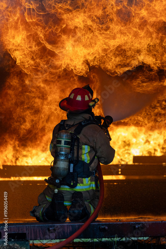 Foto Firefighter in fireproof cloth using twirl fog watering hose to put out the burn